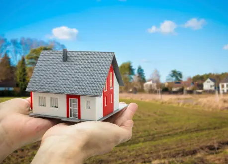 A person holding a small model house in their hand.