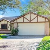 A house with a driveway and trees in the background.